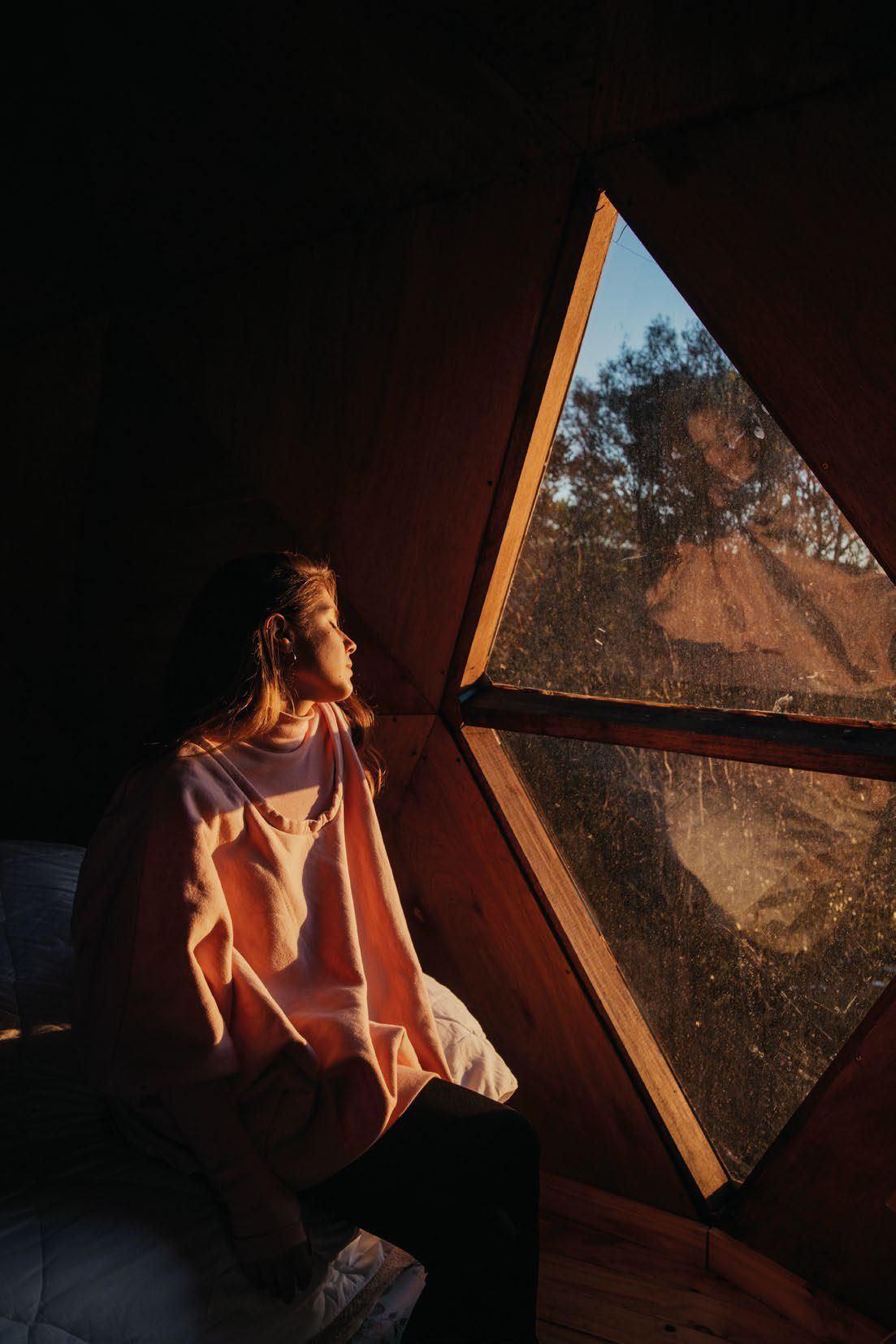 Una mujer está sentada en una cúpula mirando por una ventana.