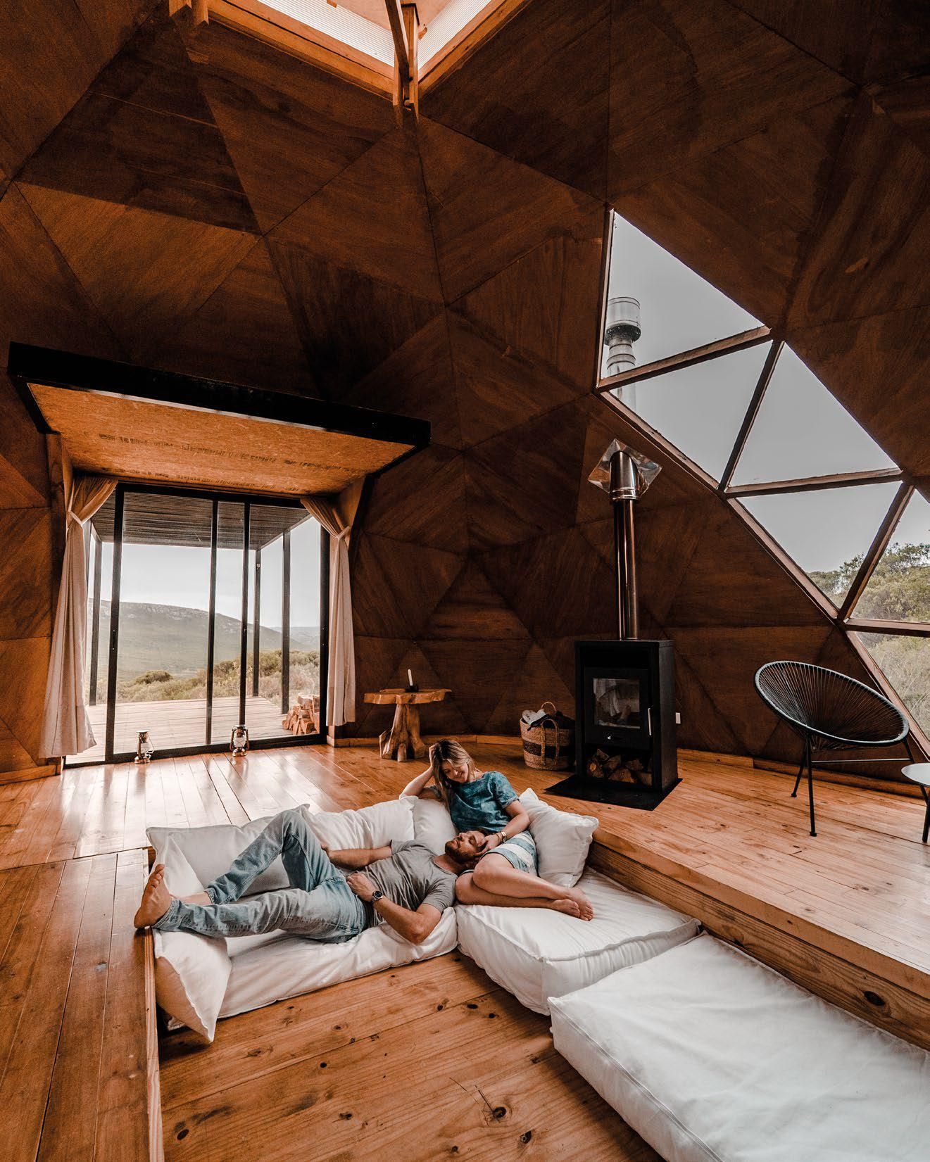 Un hombre y una mujer están tumbados en un sofá en una habitación con forma de cúpula.