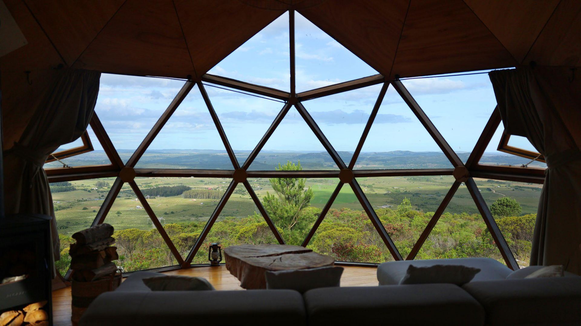 Una sala de estar con vista a un valle a través de un gran ventanal.
