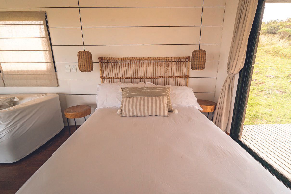 Una cama con cabecero de mimbre en un dormitorio con un gran ventanal.