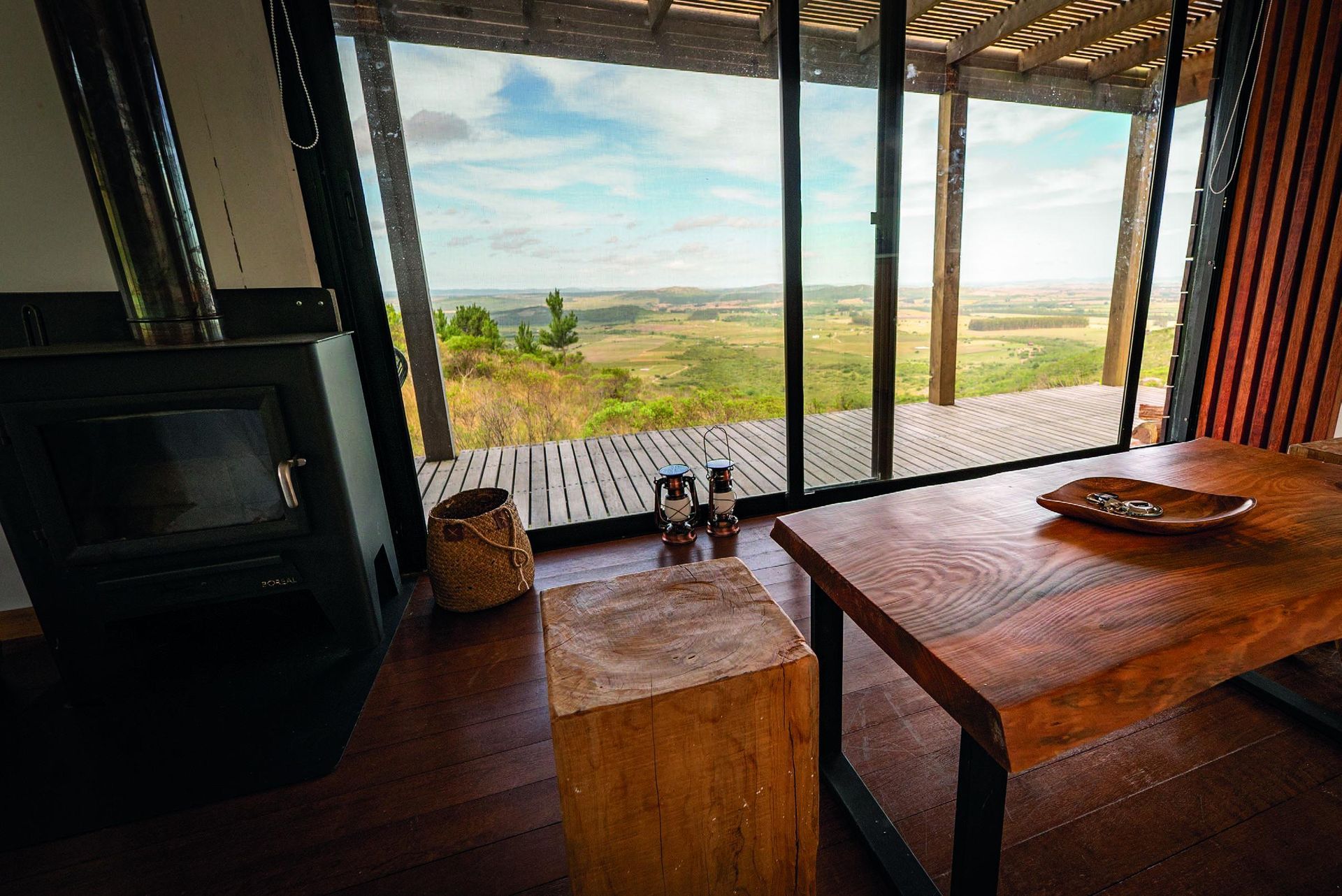 Un salón con mesa de madera, chimenea y puertas correderas de cristal.