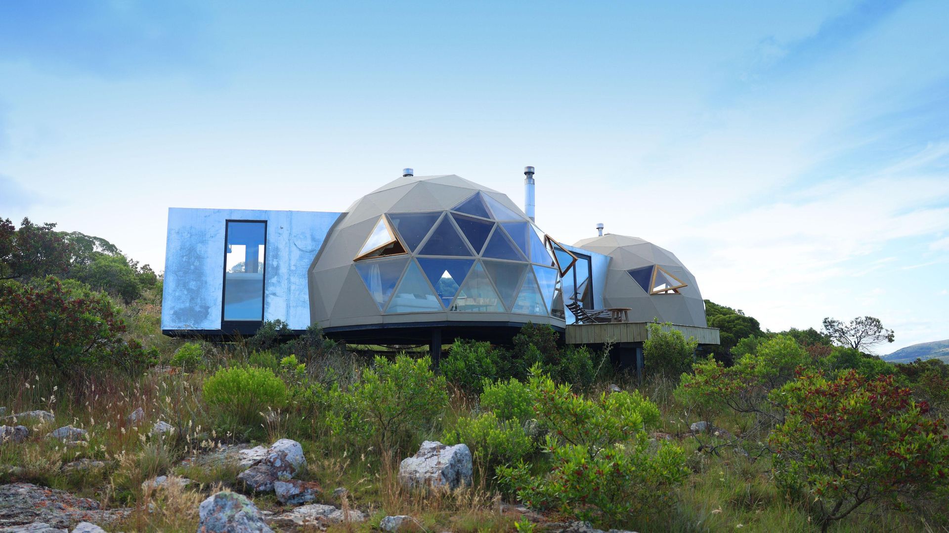 Una casa con cúpula se encuentra en la cima de una colina en medio de un campo.