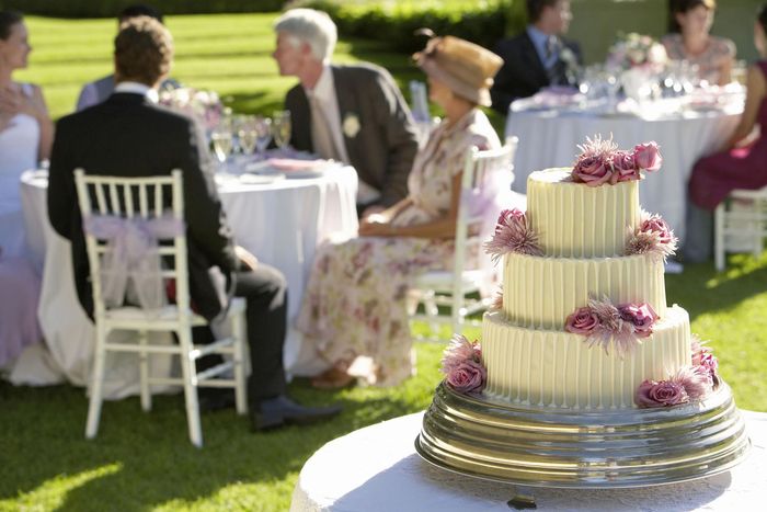 a wedding cake sits on a table with people sitting at tables in the background