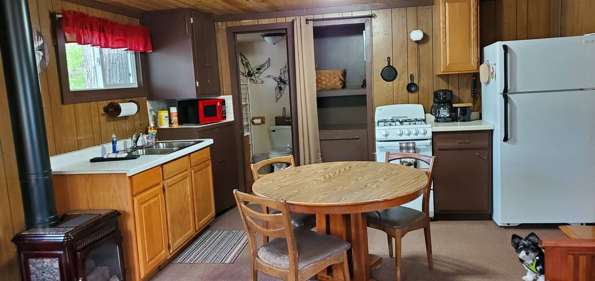 Cozy kitchen with wood cabinets, round table, white fridge, and a doorway to another room.