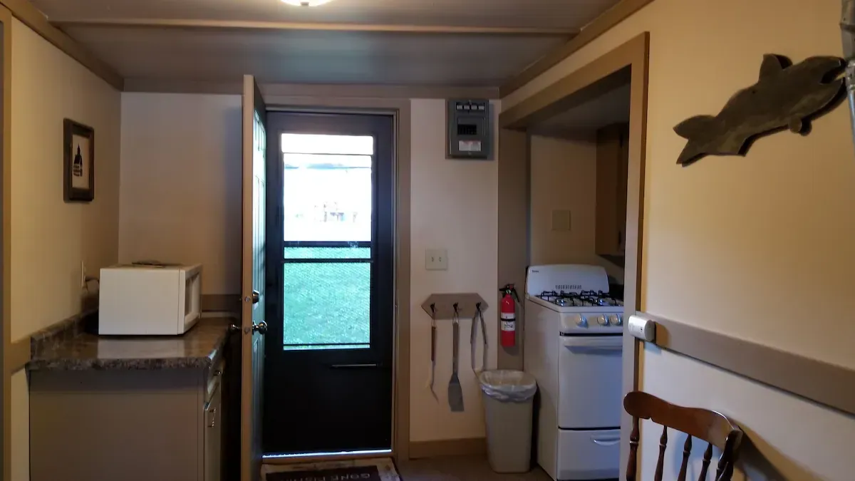 Narrow hallway with a door at the end, countertop on the left, and sink, toilet, and laundry area on the right.