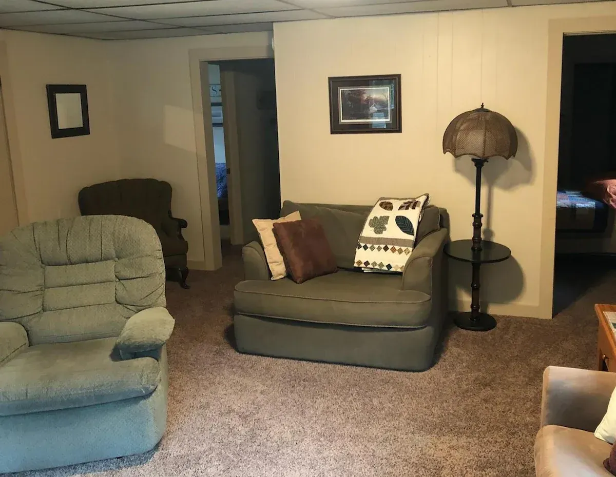 Living room with beige walls, blue recliner, gray sofa, floor lamp, and framed wall art.