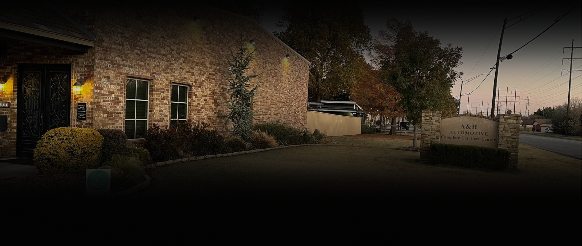 Exterior of a brick building and a sign. The scene is slightly dark, but it appears to be daytime - A&H Automotive Repair Shop