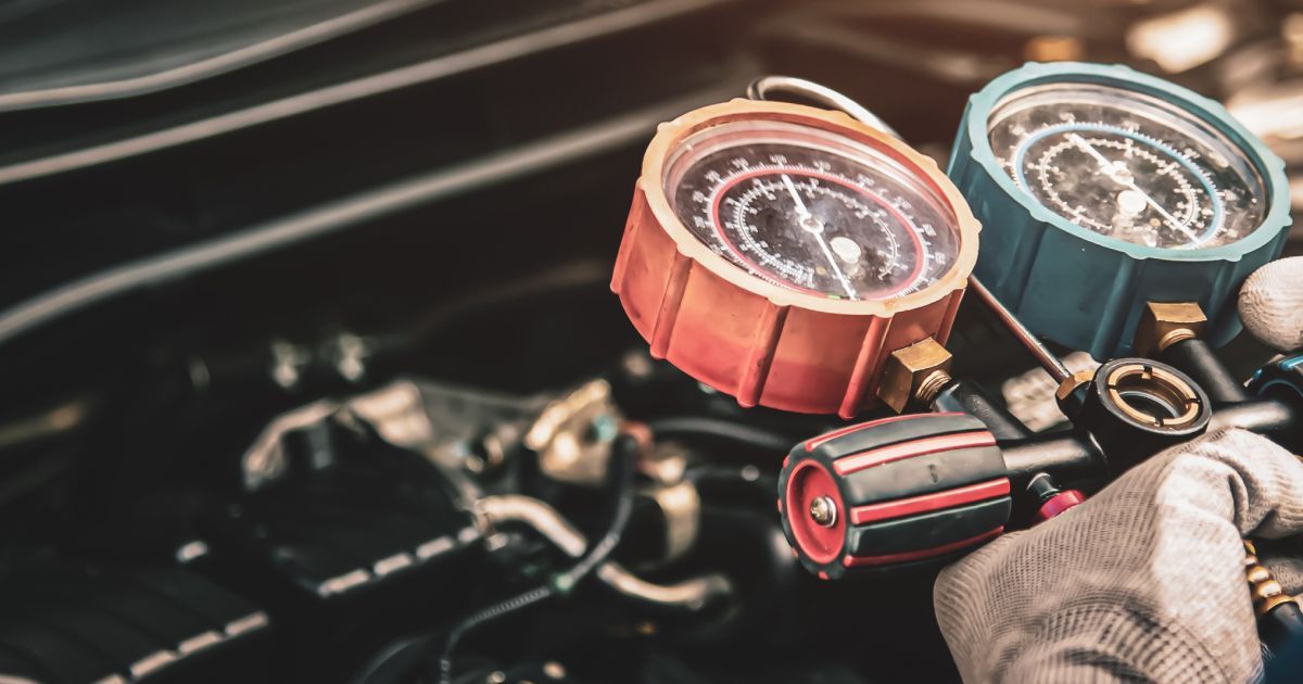 Close-up of gauges connected to a car engine; a mechanic checks the vehicle's air conditioning system.