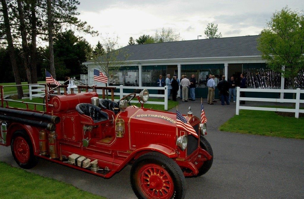 An old red fire truck is parked in front of a building