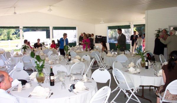 A large room with tables and chairs set up for a wedding reception