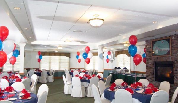 A large room with tables and chairs decorated with red white and blue balloons