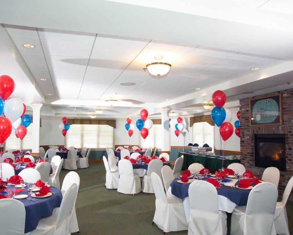 A large room with tables and chairs decorated with red white and blue balloons