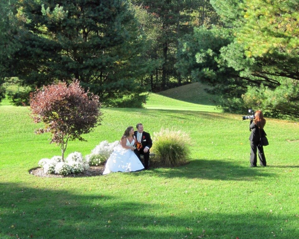 A bride and groom pose for a picture in a park