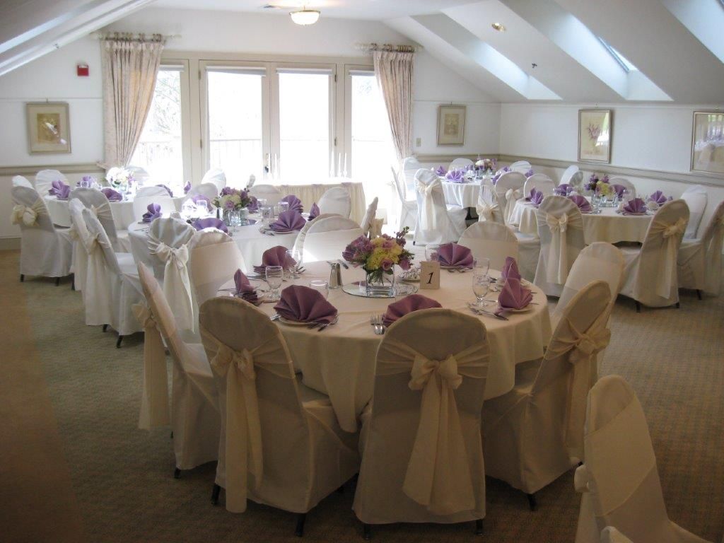 A large room with tables and chairs set up for a wedding reception