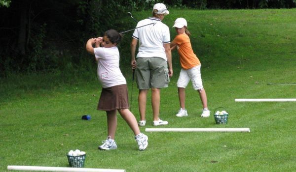 A group of people are practicing golf on a lush green field.