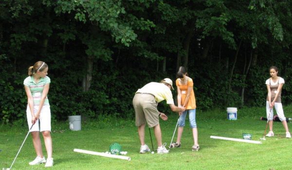 A group of people are practicing golf on a lush green field.