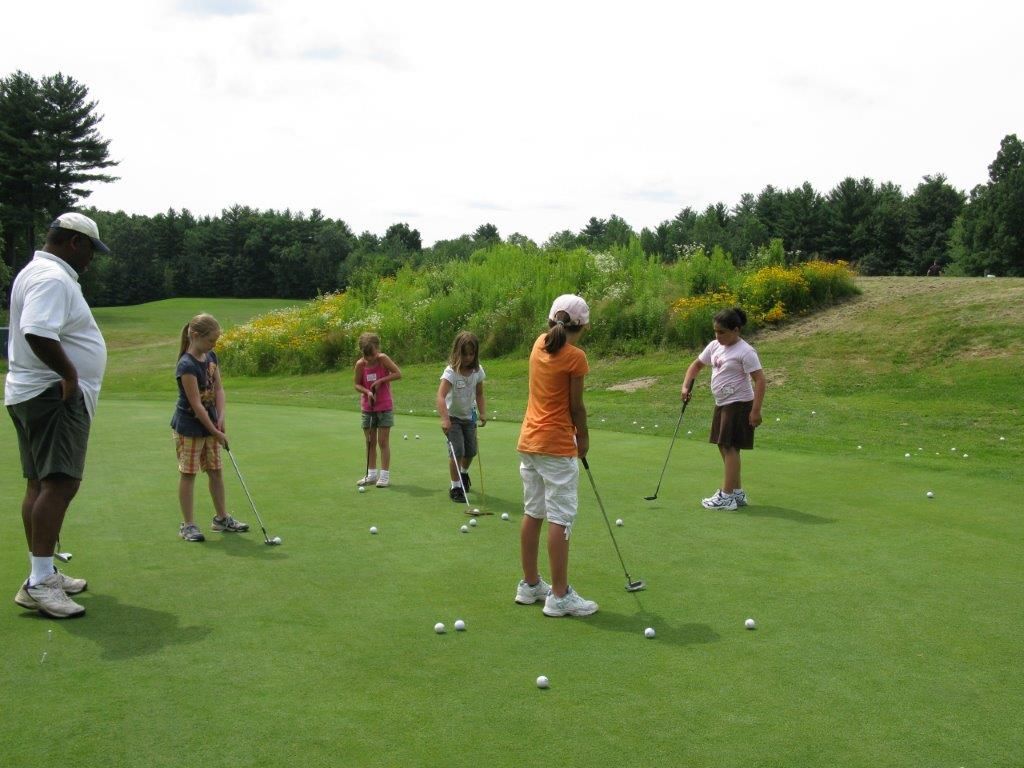 A group of children are playing golf on a green