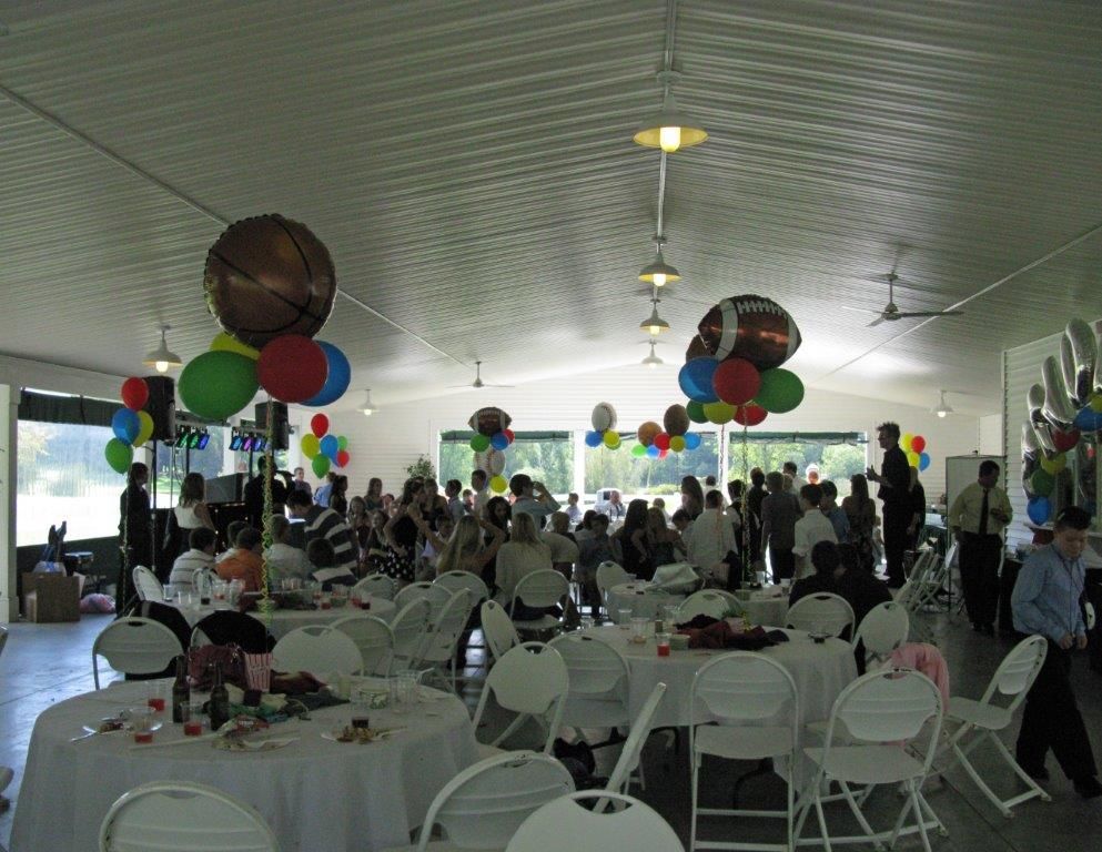 A large room with tables and chairs and balloons hanging from the ceiling