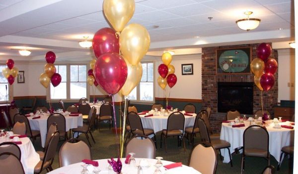 A room with tables and chairs decorated with red and gold balloons