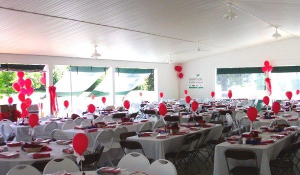 A large room with tables and chairs decorated with red balloons