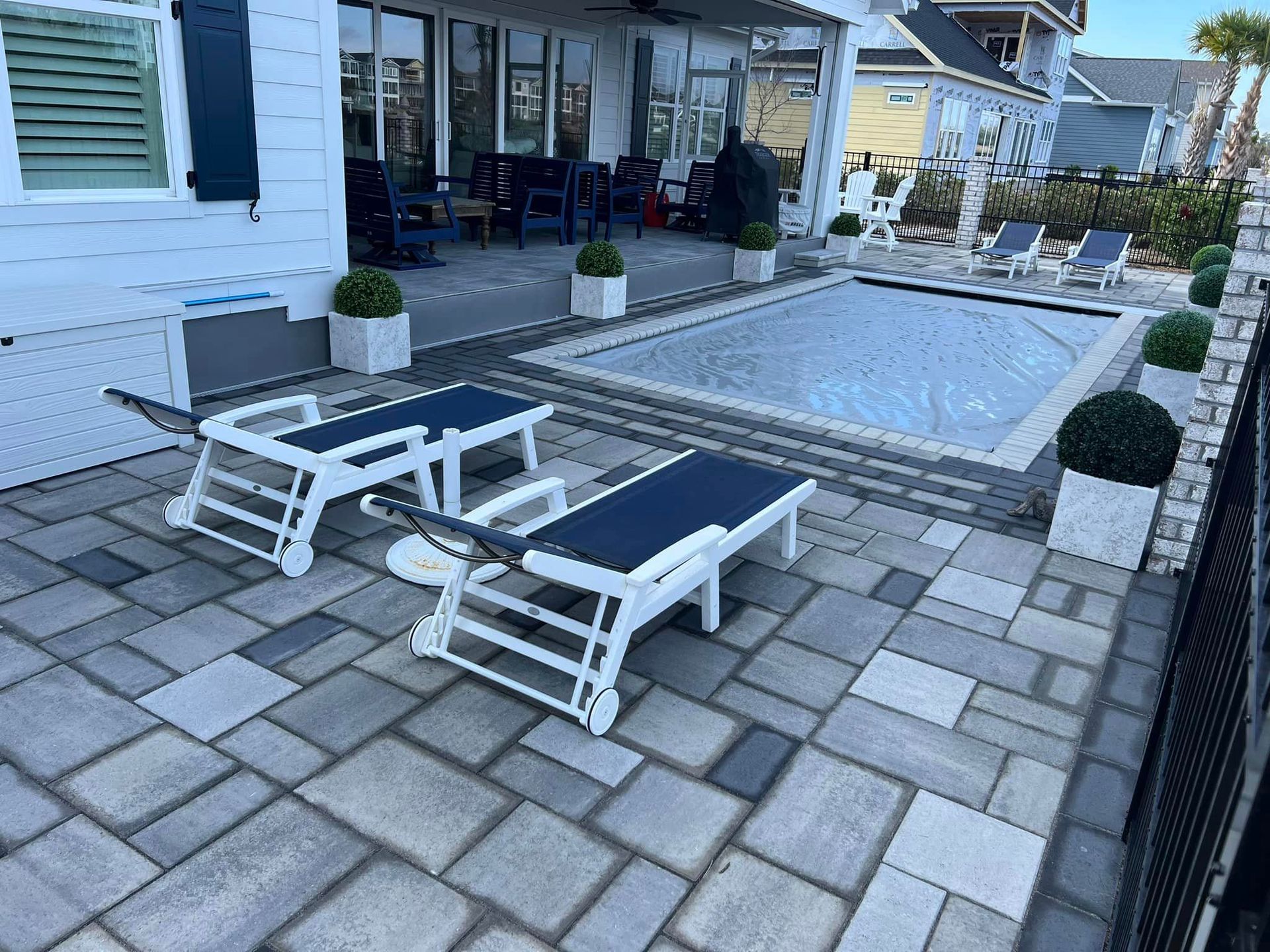 Two lounge chairs are sitting on a patio next to a pool.