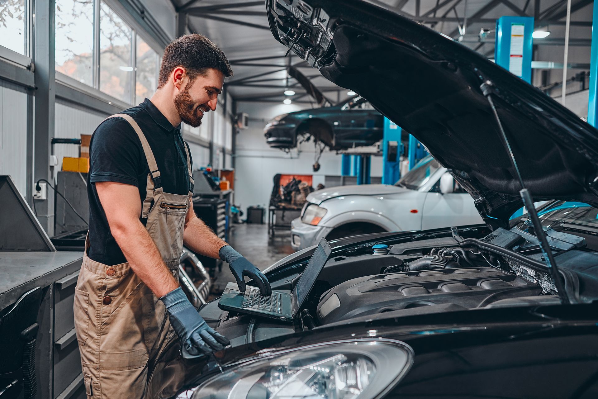 A man is working on the engine of a car in a garage.