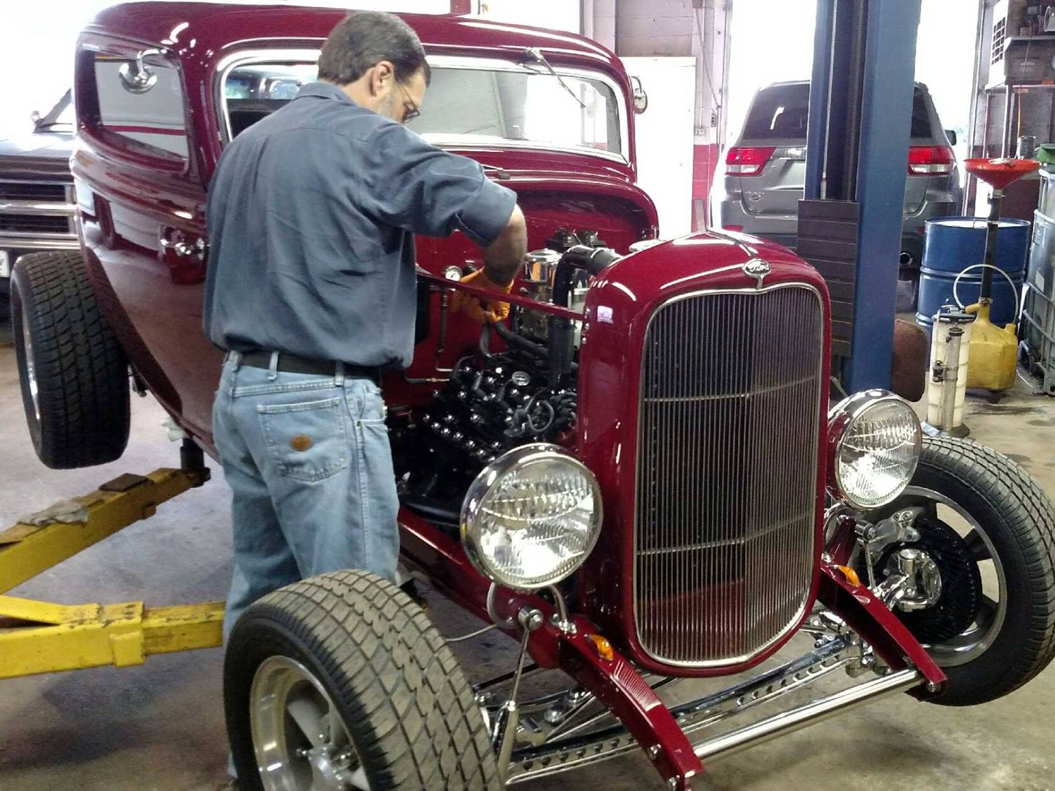 a man is working on a red car in a garage | Action Auto Service