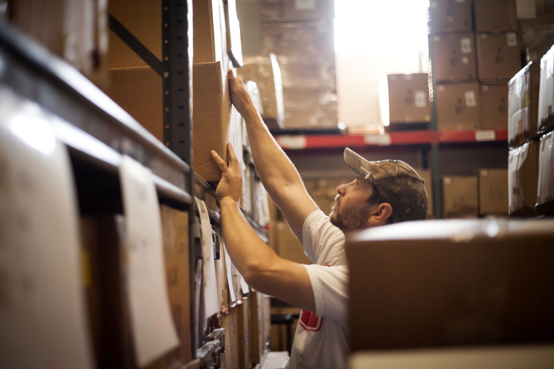worker reaching for a cardboard box stored in the warehouse
