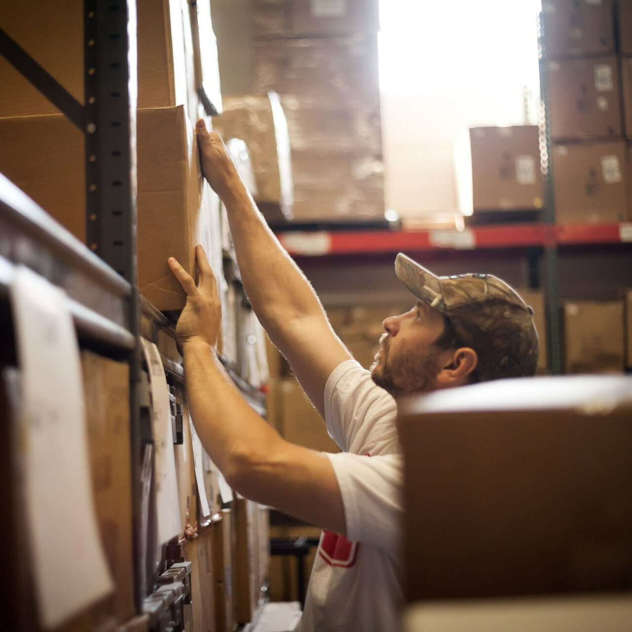 worker reaching for a cardboard box stored in the warehouse