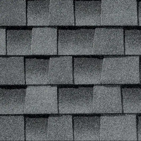 Close-up of overlapping gray asphalt roof shingles with varying shades and textures.