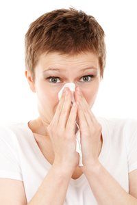 A woman is blowing her nose with a napkin.