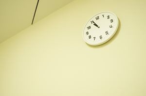 A white clock is hanging on a white wall.