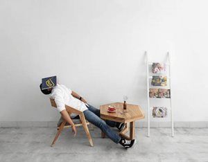 A man is sleeping on a chair with a book on his head.