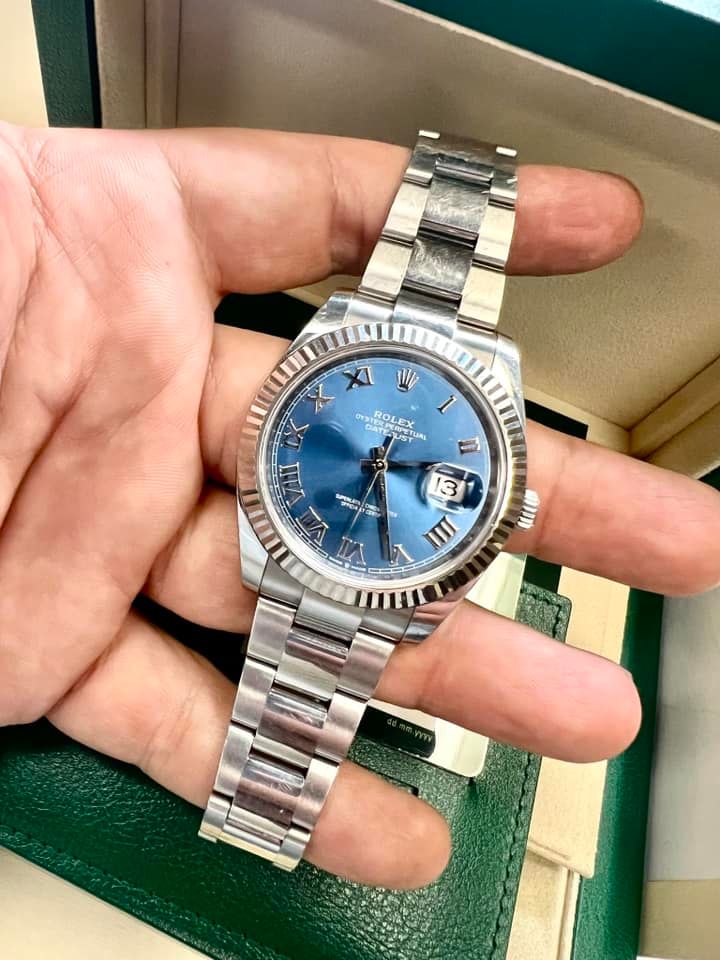 Silver Rolex watch with a blue face on a person's hand.