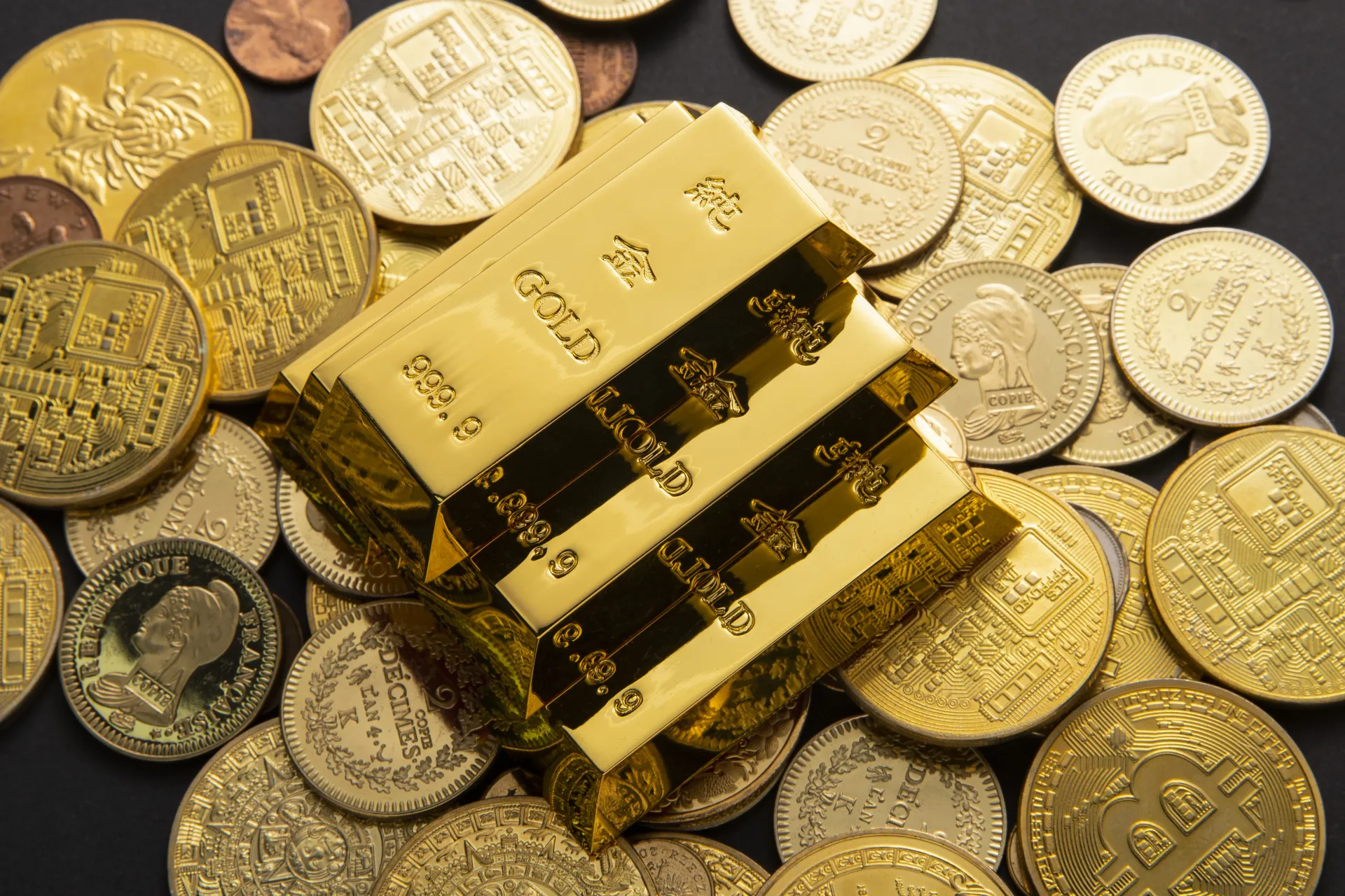 Gold bars stacked on assorted gold and silver coins