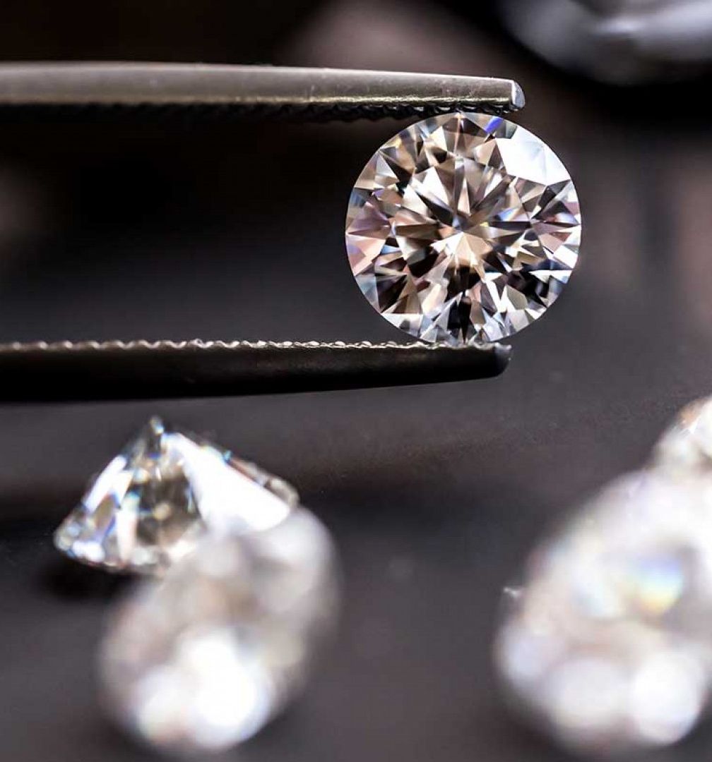 A close up of a pair of tweezers holding a diamond.