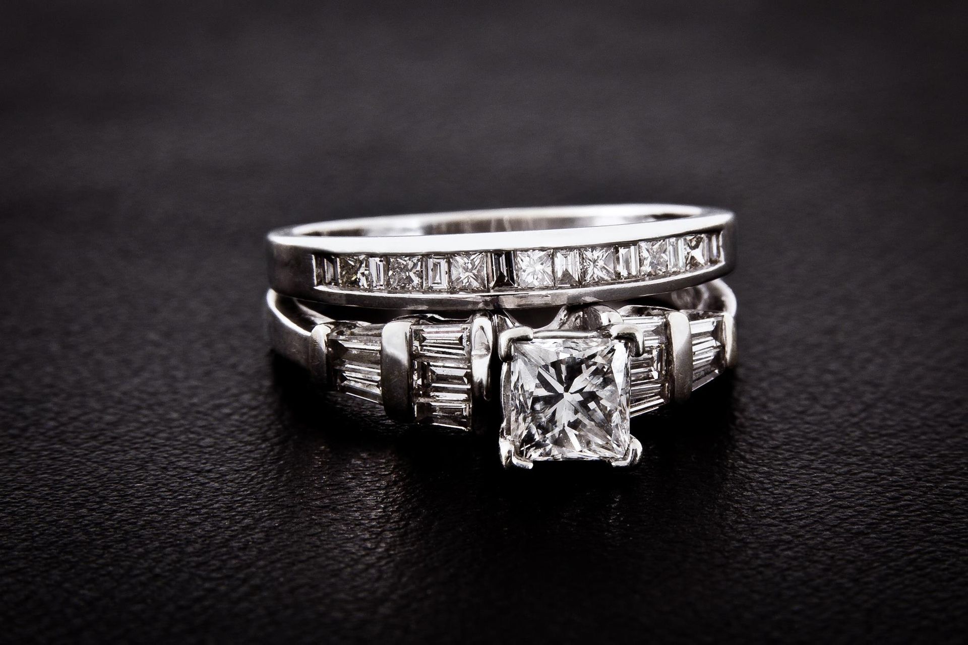 A wedding ring and engagement ring are stacked on top of each other