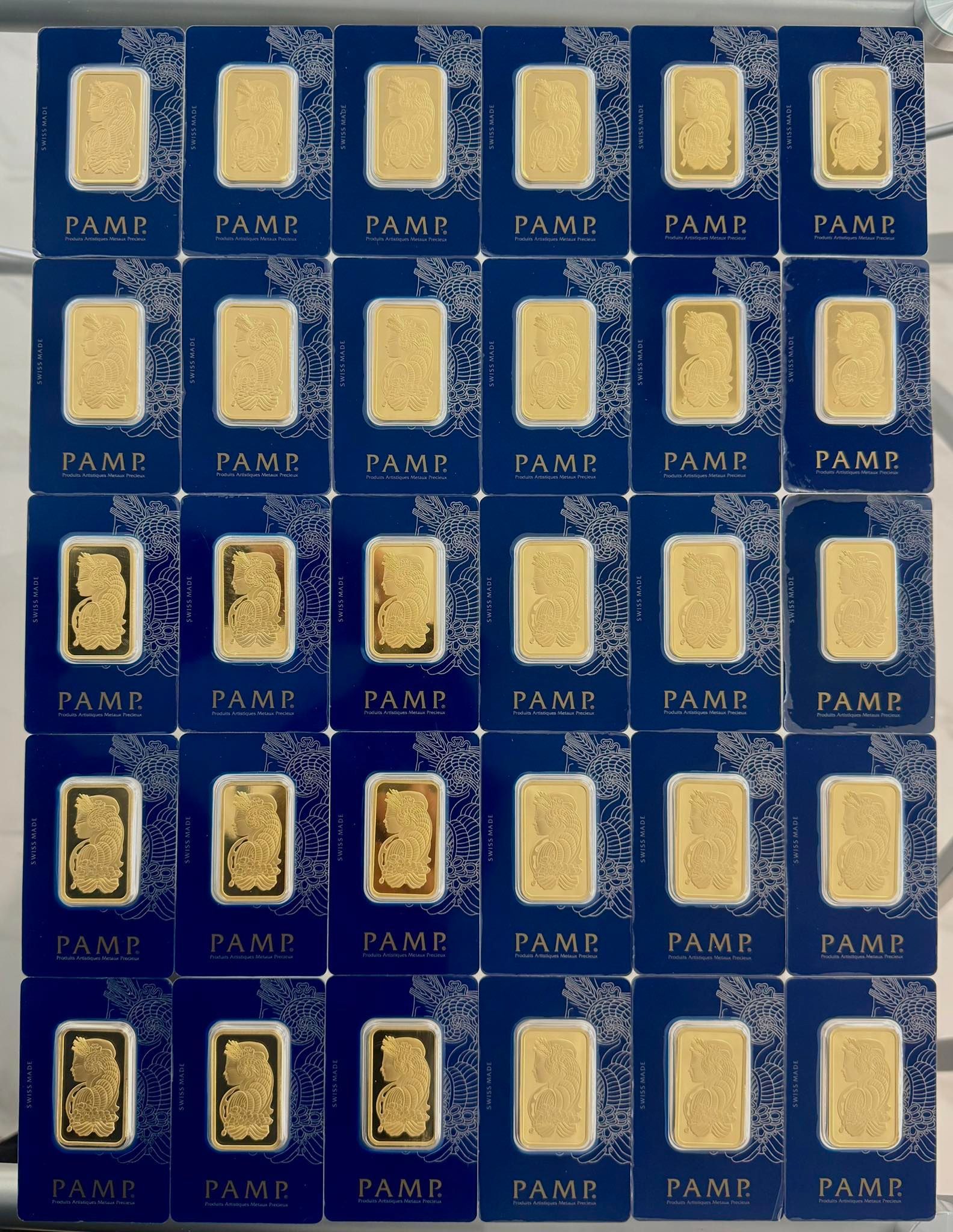 Rows of gold bars encased in blue PAMP Suisse packaging.
