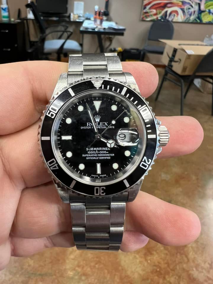 A person is holding a rolex watch in their hand.