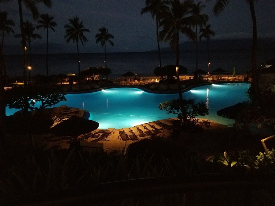 A large swimming pool is lit up at night