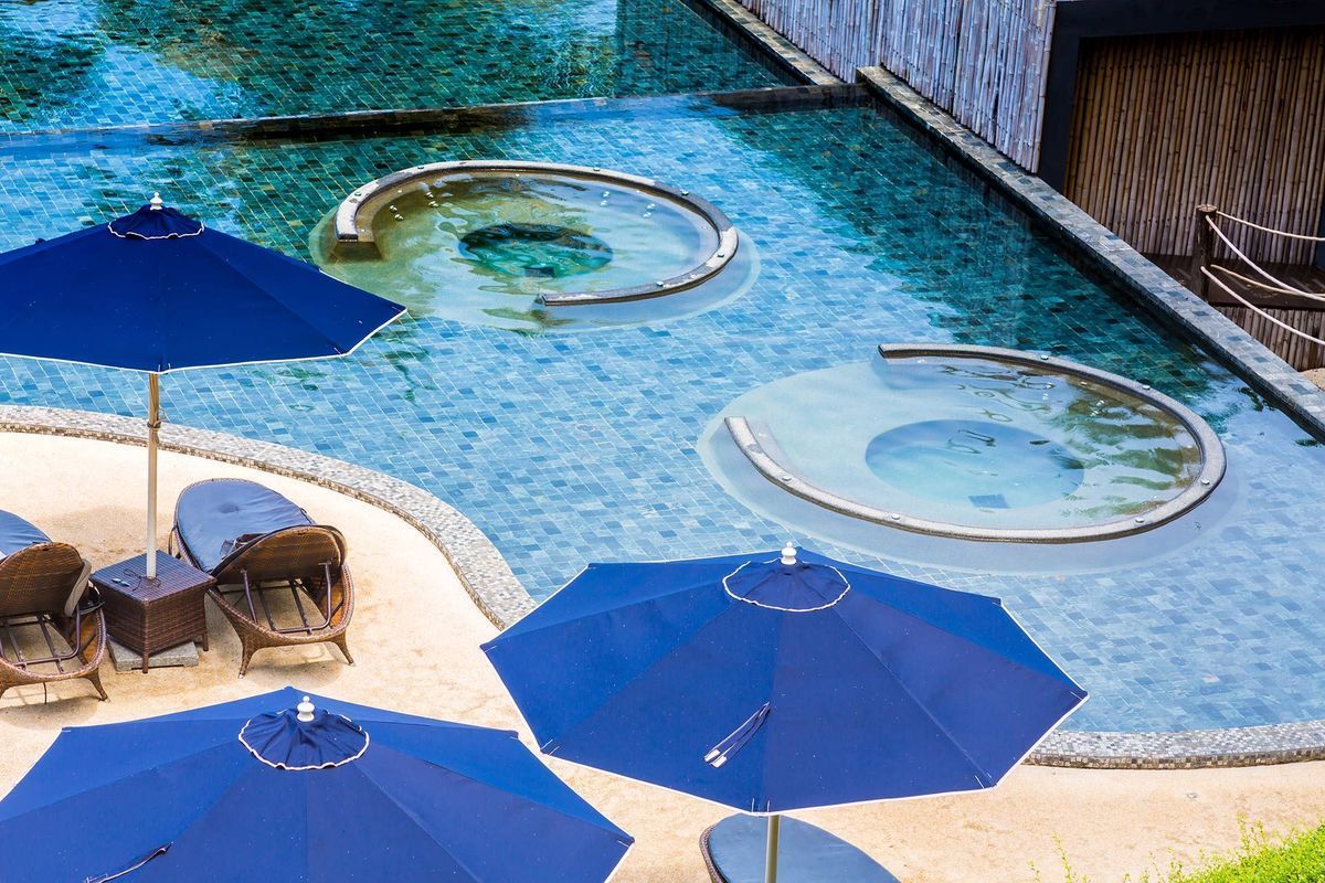 A swimming pool with blue umbrellas and chairs around it