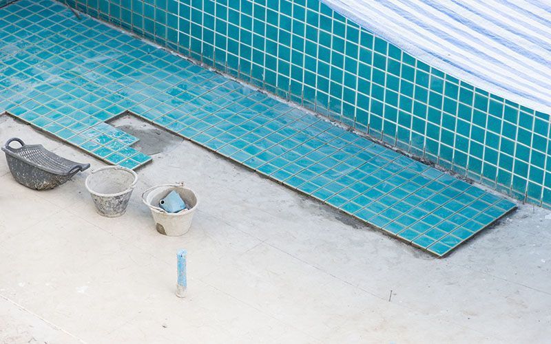 The tiles are being installed on the side of a swimming pool.