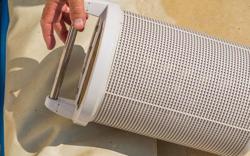 A person is holding a white filter on a beach.