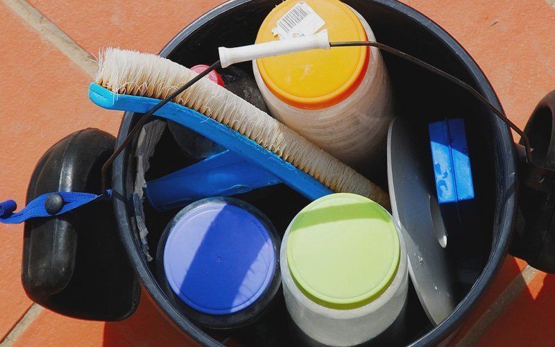 A bucket filled with cleaning supplies including a brush