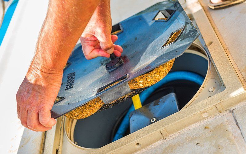 A person is cleaning a drain on a boat with a brush.