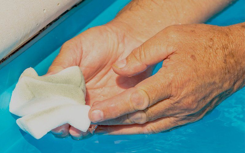 A person is washing their hands in a pool with a towel.