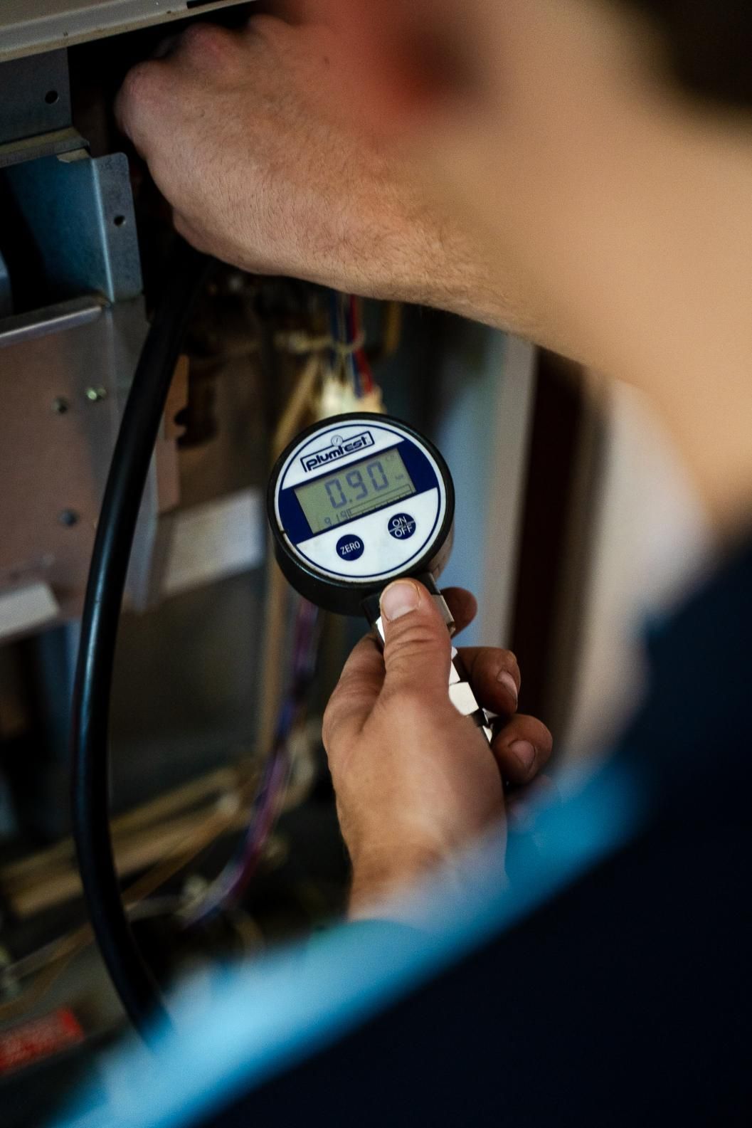 A Man is Holding a Digital Pressure Gauge in His Hand — Wello's Plumbing & Gas In Wodonga, VIC
