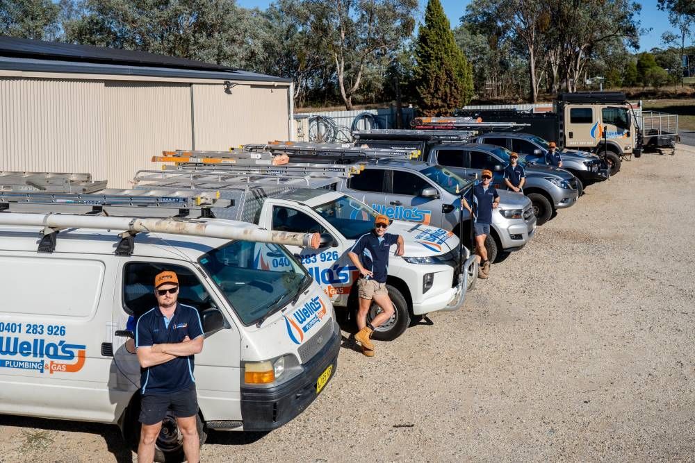 A Man is Standing in Front of a Row of Vans — Wello's Plumbing & Gas in Thurgoona, NSW
