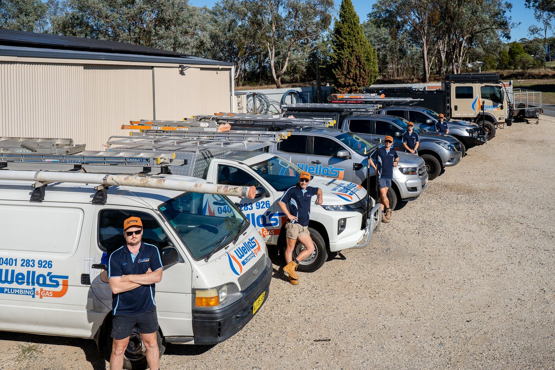 A Group of People Standing in Front of a Brick Wall — Wello's Plumbing & Gas In Thurgoona, NSW