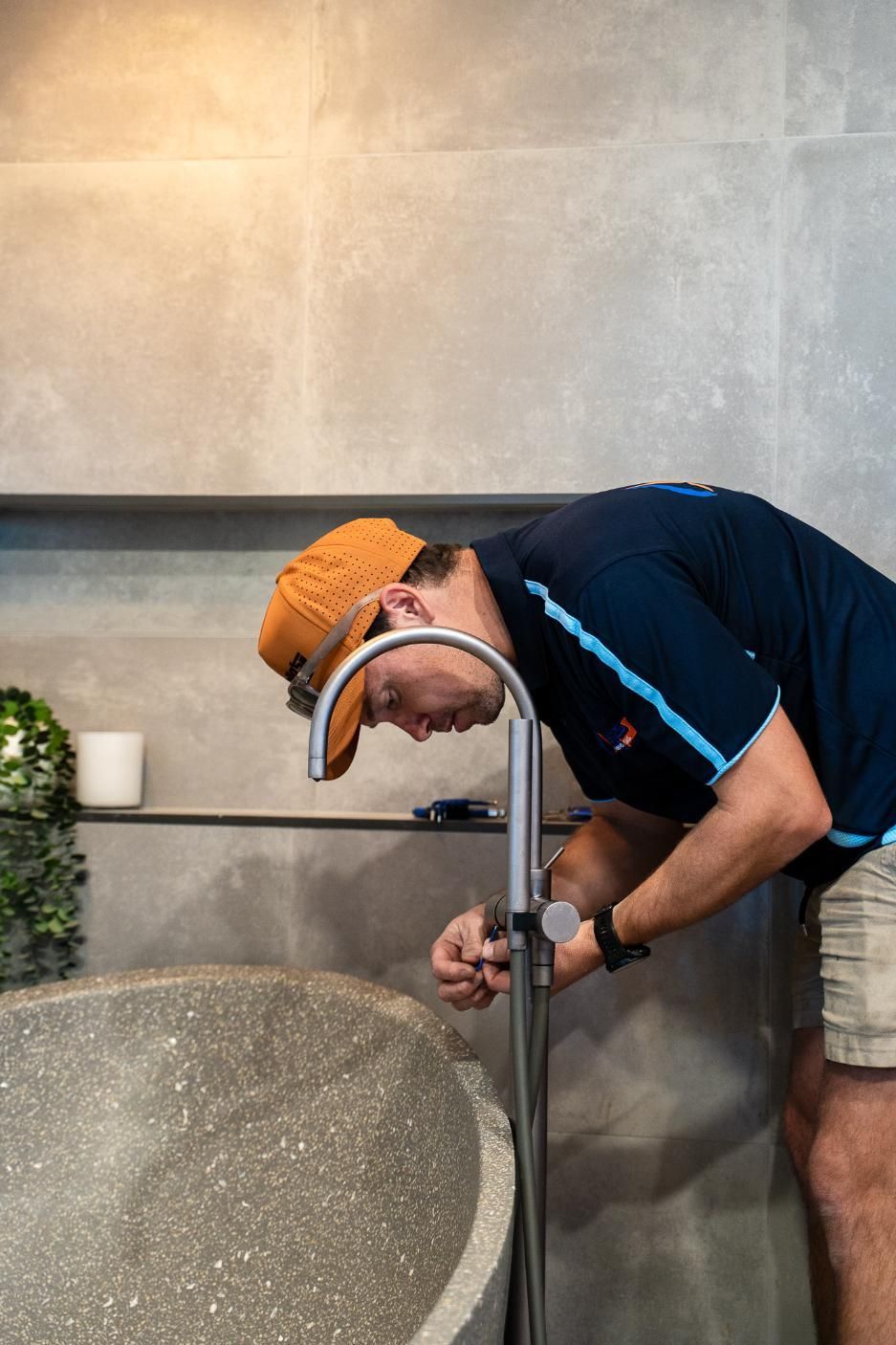 A Man is Fixing a Faucet in a Bathroom — Wello's Plumbing & Gas In Thurgoona, NSW